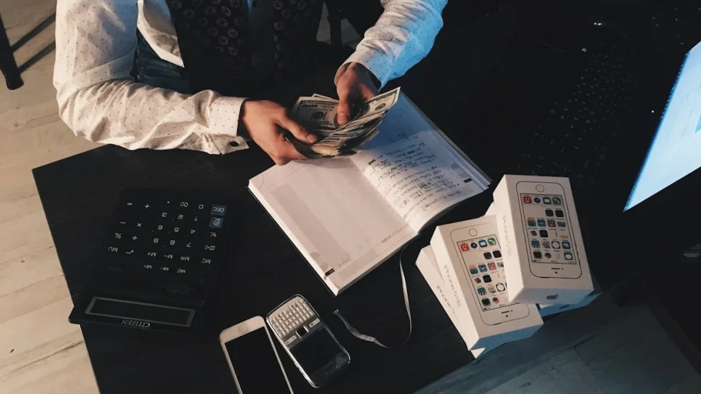 Accountant entering invoice data into a computer with printed invoices, calculator, and pen on the desk, illustrating invoice processing and indirect tax management. Source: Pexels